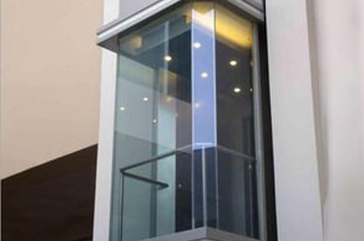 The elevator features transparent glass panels, allowing clear visibility and a sense of openness.